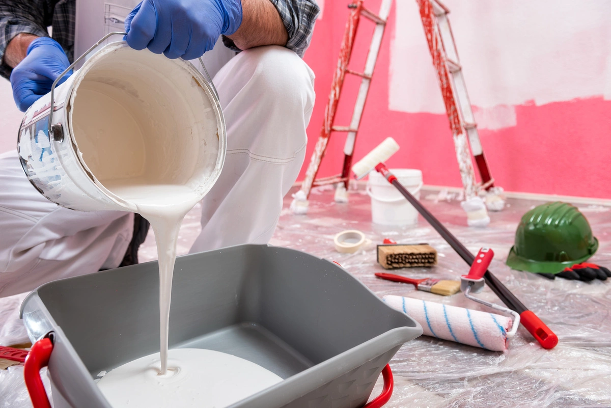 professionnel versant un pot de peinture blanche dans un seau